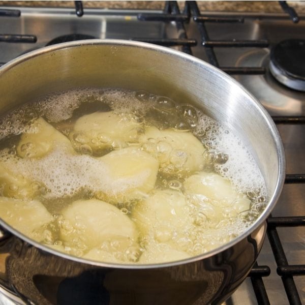 Kooritud kartulid vee sees keemas.