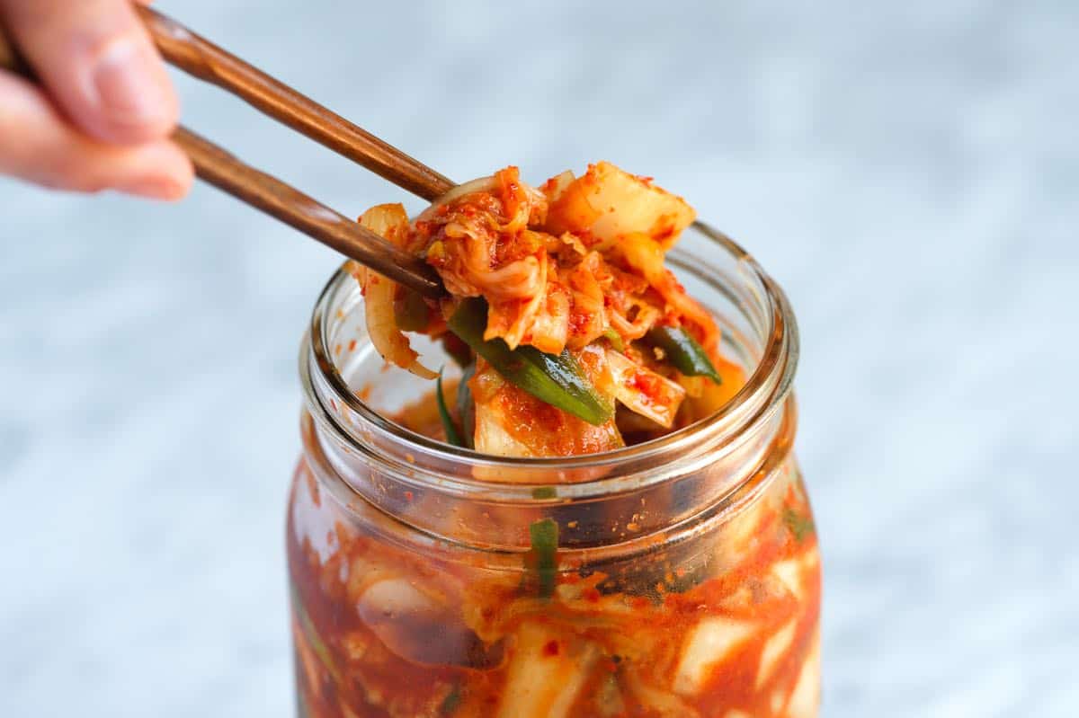 Kimchi võtmine purgist pulkade vahel.
